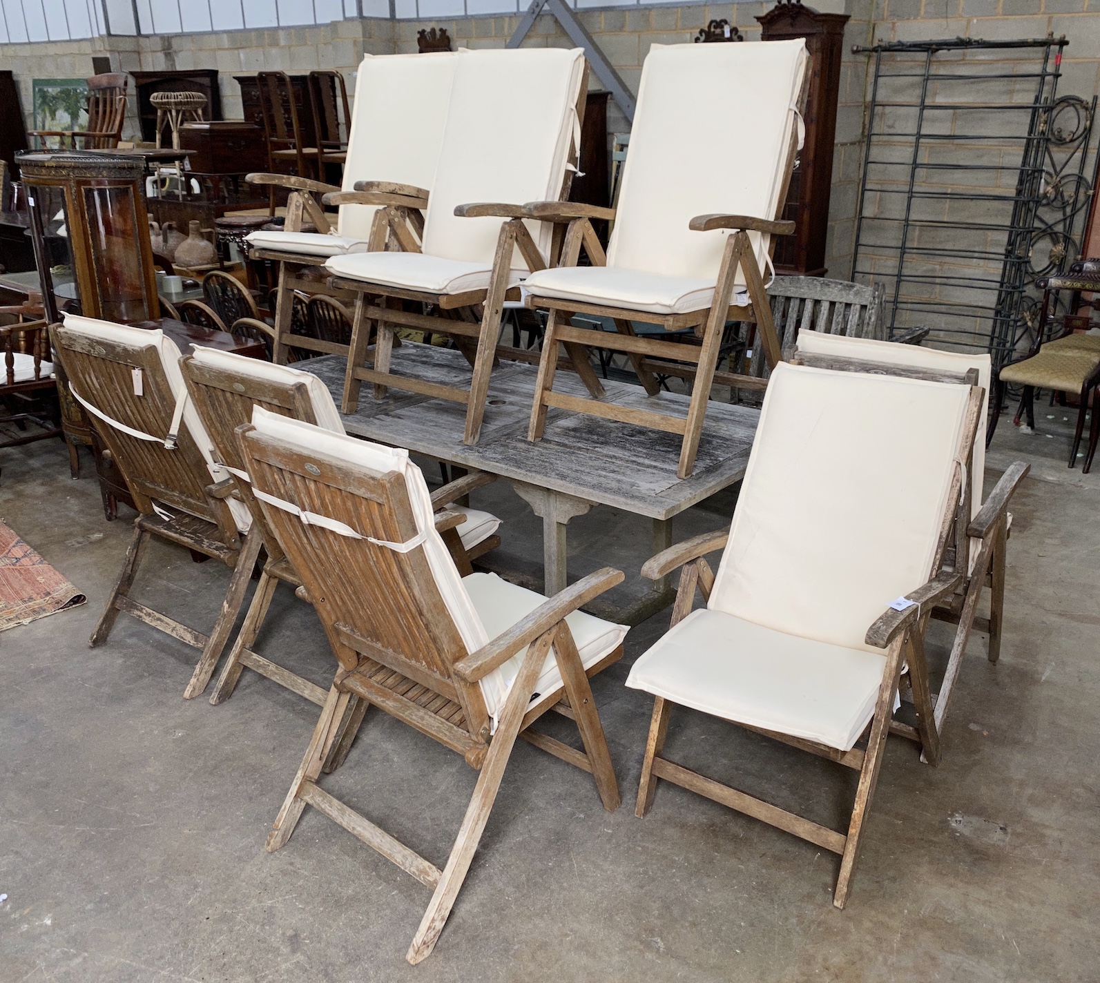 A Lindsey rectangular weathered teak extending garden table, 200cm extended, depth 94cm, height 75cm and eight Royal teak folding garden elbow chairs with seat cushions